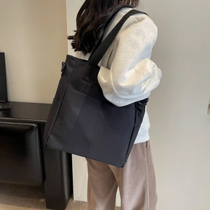 Vue détaillée du sac cabas en nylon noir imperméable porté par un mannequin en studio