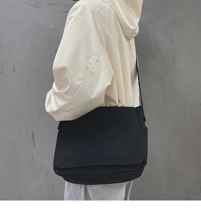 Vue de dos d'un grand sac bandoulière en toile noire sur un mannequin aux tons neutres