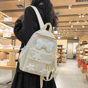 Detail of a creamy nylon backpack with cute plush stars and bone-shaped decorations