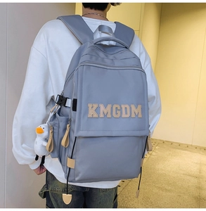 Detail of grey nylon backpack with KMGDM embroidery and cute white duck charm