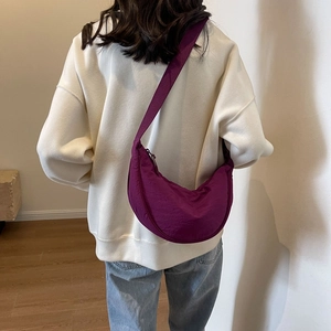 Rear view of a purple crescent-shaped nylon crossbody bag with adjustable wide strap