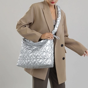 Detail showing metallic silver heart quilted nylon tote bag worn on shoulder by model