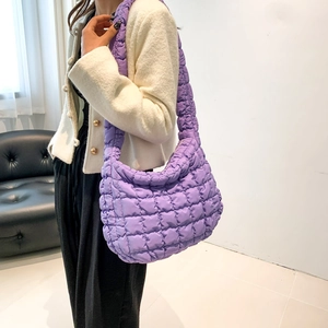 Detailed close-up showing the purple quilted cotton texture of the puffer shoulder bag