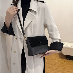 Vue détaillée du sac bandoulière noir en daim et cuir porté par un mannequin chic