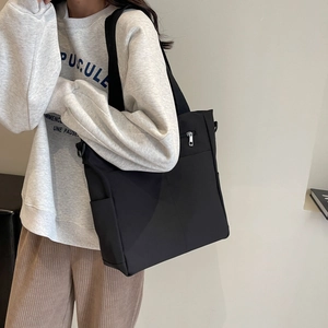 Détail du sac à bandoulière en nylon imperméable avec zip argenté et poche latérale