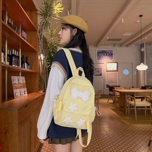 Detail view of yellow nylon backpack featuring plush white bow and star decorations