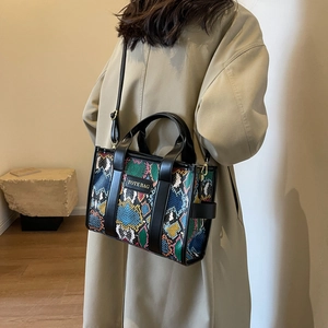 Detail of vibrant snakeskin pattern tote bag with leather straps on a beige coat