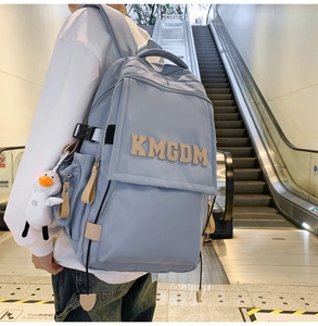 Detail of blue nylon backpack with white duck charm and KMGDM letter decor