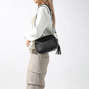 Sac bandoulière noir minimaliste avec sangle large géométrique porté par un mannequin