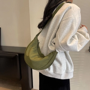 Detailed side view of the grass green nylon crescent moon crossbody bag on a model