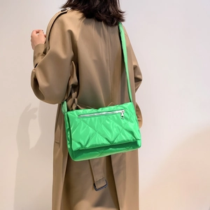 Dettaglio di una borsa trapuntata verde brillante indossata con un trench kaki alla moda