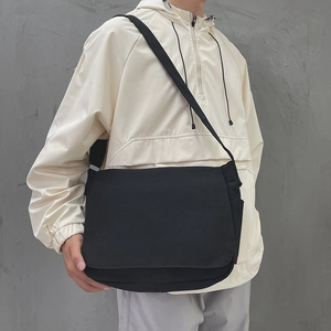 Sacoche minimaliste en toile noire avec grand rabat et sangle réglable sur un mannequin homme
