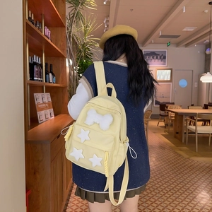 Detail of light yellow nylon backpack with plush bow and stars decoration on a model