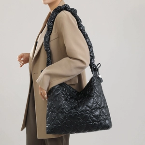 Detail of a black heart-quilted nylon shoulder bag with stylish ruched handle design