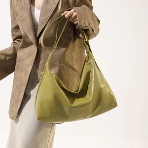 Detail of avocado green PU leather tote bag with vintage pleated texture and crescent shape