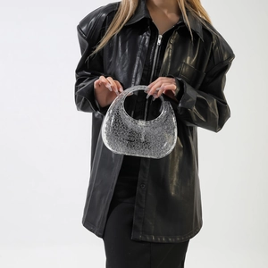 Detail of transparent acrylic handbag featuring circular textures and silver metal clasp