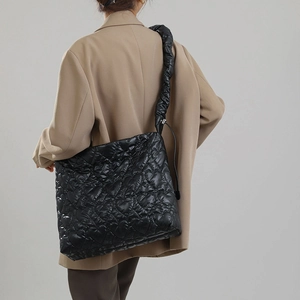 Detail of black quilted nylon handbag with heart-shaped patterns and pleated shoulder strap