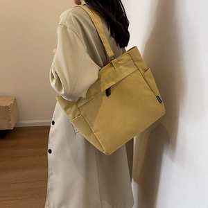 Detail of ginger yellow canvas tote bag with side pocket and fashion label for casual wear