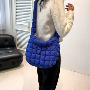 Klein blue quilted puff crossbody bag shown from a side-view perspective on a model