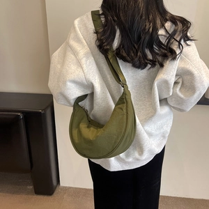 Detail of army green nylon half-moon crossbody bag shown on model for size and fit