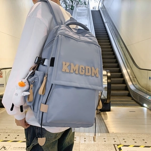 Minimalist light blue nylon backpack with KMGDM letters and white duck plush keychain