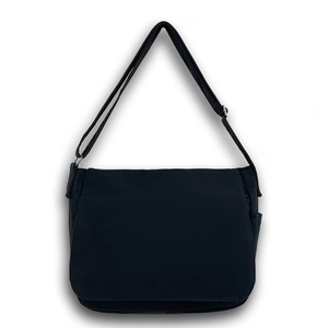 Sac bandoulière minimaliste en toile noire avec sangle réglable et rabat sur fond blanc