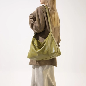 Detail of the olive green hobo bag showing the glossy PU leather texture and shoulder strap