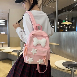 Pink nylon backpack detail showing plush white bow and stars decoration on female model