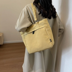 Close-up of bright yellow canvas tote bag with zipper closure and black fashion label