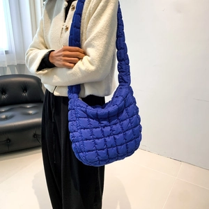Close-up of klein blue quilted nylon shoulder bag with soft padded texture and stitching