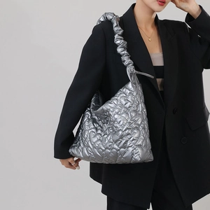Detail of silver heart-quilted puffer bag with scrunchie strap shown on model shoulder