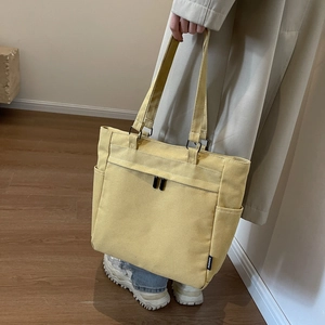 Detail view of mustard yellow canvas tote bag with dual shoulder straps and side pocket