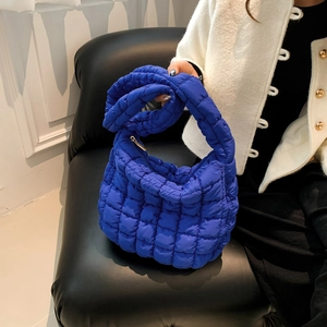 Detail of blue quilted bubble fabric hobo bag with thick handle and golden zipper