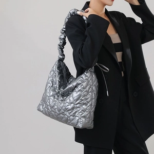 Close-up of silver quilted shoulder bag with heart pattern and pleated strap detail