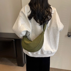 Olive green nylon crescent crossbody bag worn over a grey sweatshirt for a casual style