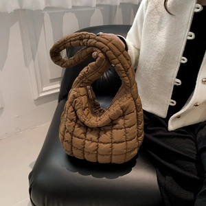 Detail of a brown quilted bubble handbag showing thick padded handles and puffer texture