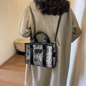 Chic grey python print tote bag with black leather straps shown on a model