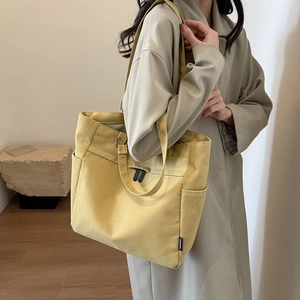 Detail view of large ginger yellow canvas tote bag with side pockets on a model