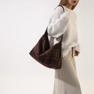 Close-up of vintage plaid Hobo bag with wide leather strap on a model's shoulder