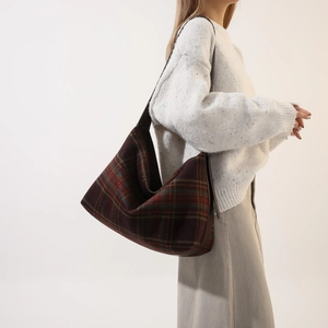 Detail of vintage plaid hobo bag featuring wool texture and brown leather strap