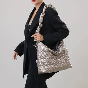 Detail of silver heart-quilted nylon handbag with ruffled shoulder strap on model