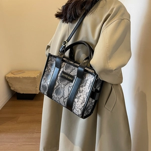 Close-up of snakeskin pattern tote bag with leather trim and adjustable shoulder strap
