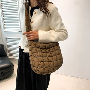 Brown quilted crossbody bag showing soft polyester fabric and crescent shape on model