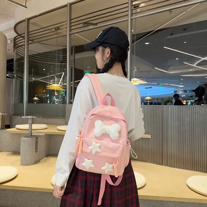 Close-up of a pink nylon backpack featuring a white plush bow and star charms decoration