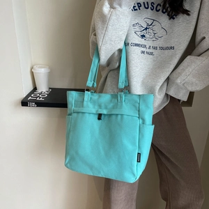 Detail view of light green canvas tote bag showing side pocket and durable fabric texture