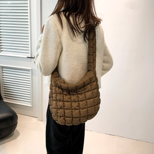 Detail of a brown quilted bubble puffer shoulder bag showing soft nylon texture and wide strap