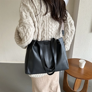 Detail of black PU tote bag featuring a vintage woven shoulder strap and matte finish