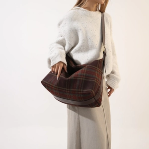 Detailed view of red and green plaid wool hobo bag with a brown leather shoulder strap