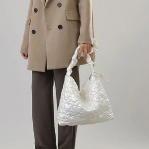 Detail of white glossy heart-quilted nylon handbag with elegant ruched handle design