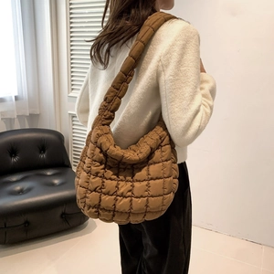 Detail view of brown quilted crossbody bag with soft bubble texture and wide shoulder strap